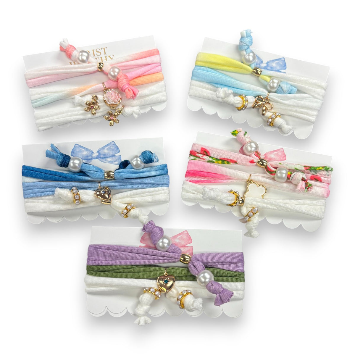 Five coquette hair tie sets in pastel stretch fabrics with pearls and gold charms