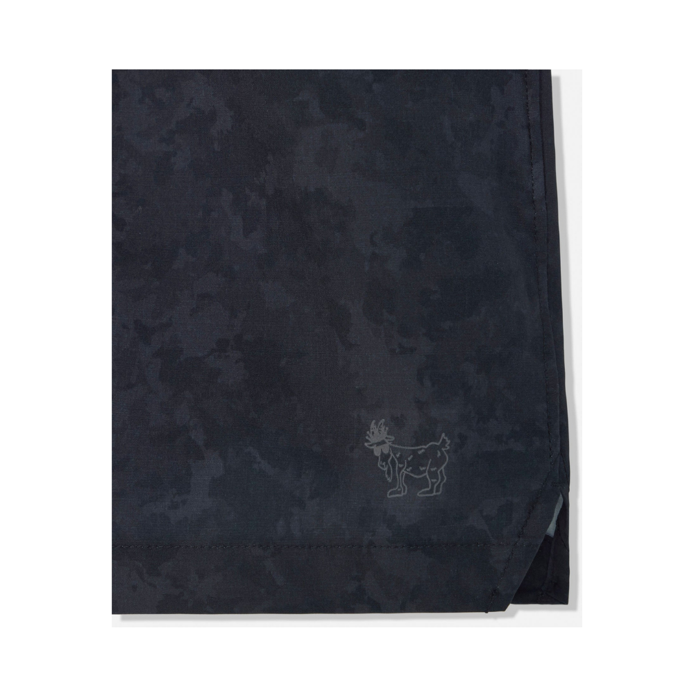 Detail shot of GOAT logo embroidered on lower left hem of navy camo athletic shorts