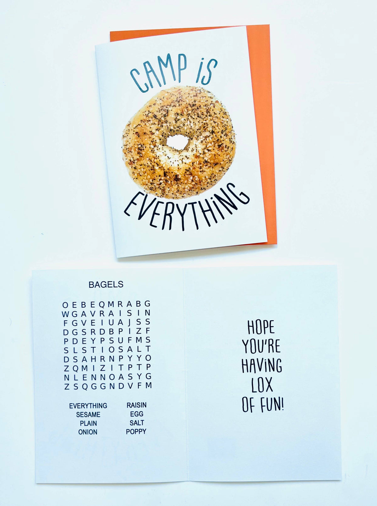 Camp Is Everything greeting card with everything bagel photo and playful text, displayed with orange envelope on light blue background
