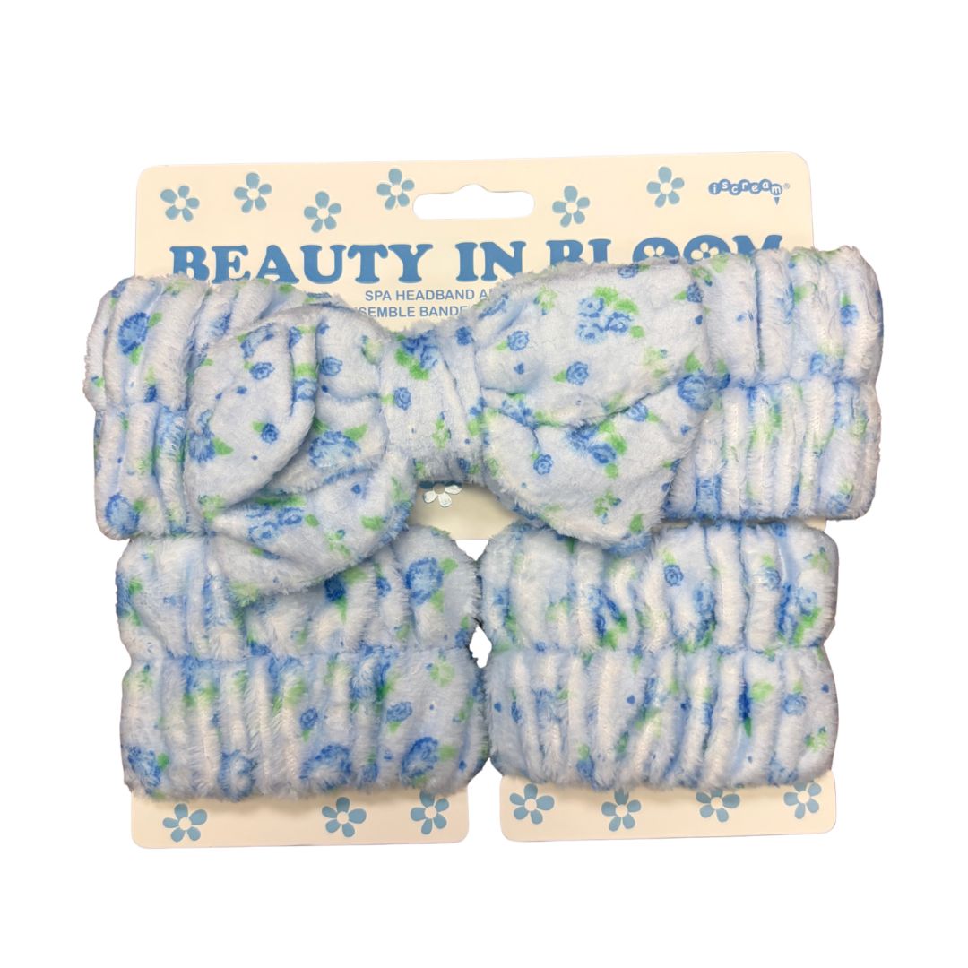 Blue ditsy spa headband set with soft white fluffy terry material featuring small blue floral print and bow detail, displayed on peach cardboard packaging with Beauty in Bloom text