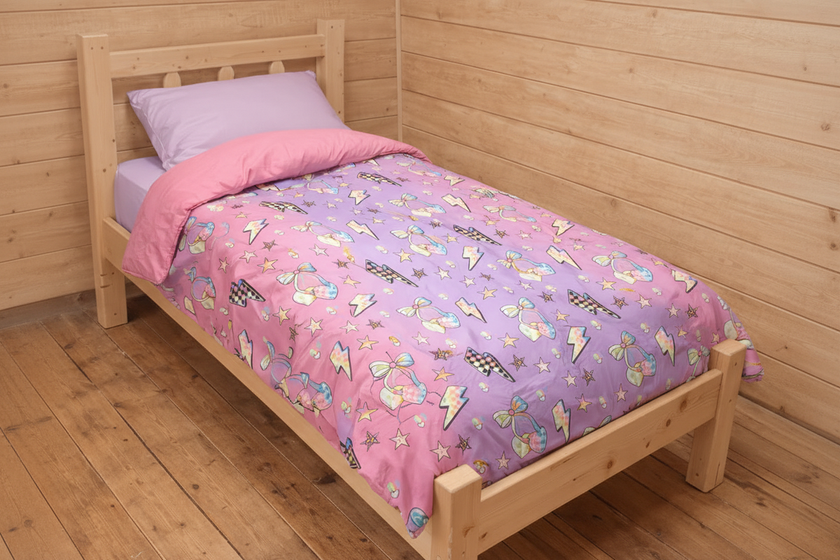 Camp comforter with cherries and bolts in pink and purple ombre on a bed