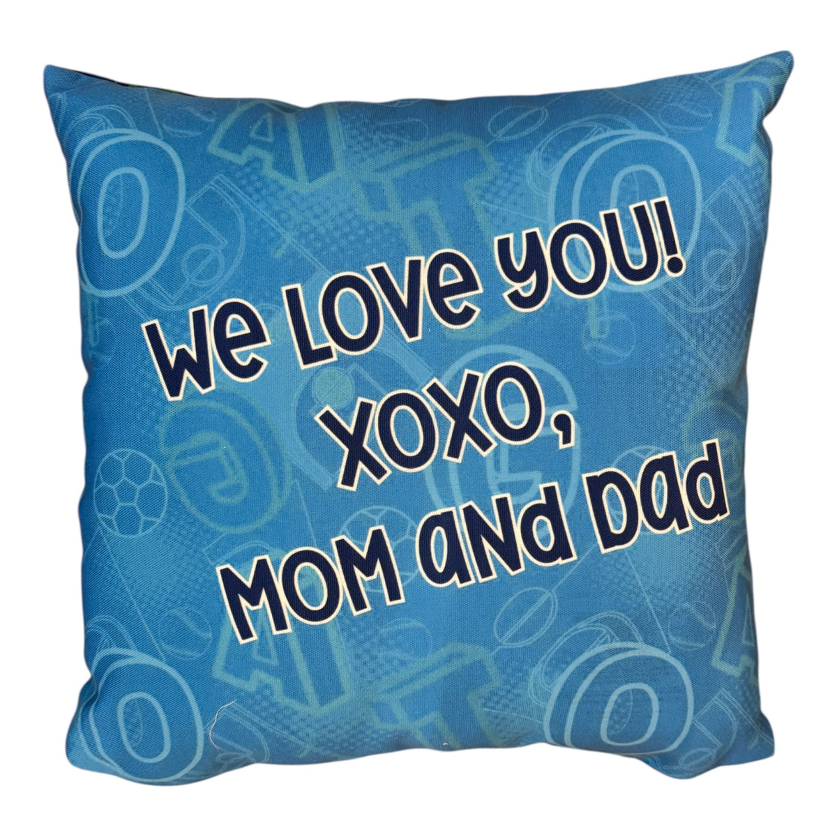 Back side of G.O.A.T. personalized pillow with message We Love You XOXO Mom and Dad on blue patterned background