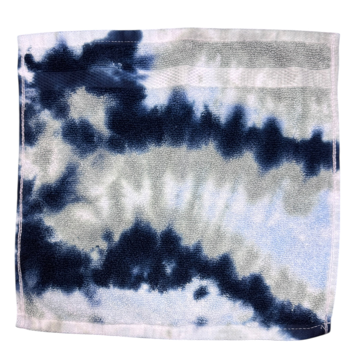 Julius tie dye terry washcloth in navy blue, gray, and white swirled pattern, folded and displayed flat showing soft cotton texture