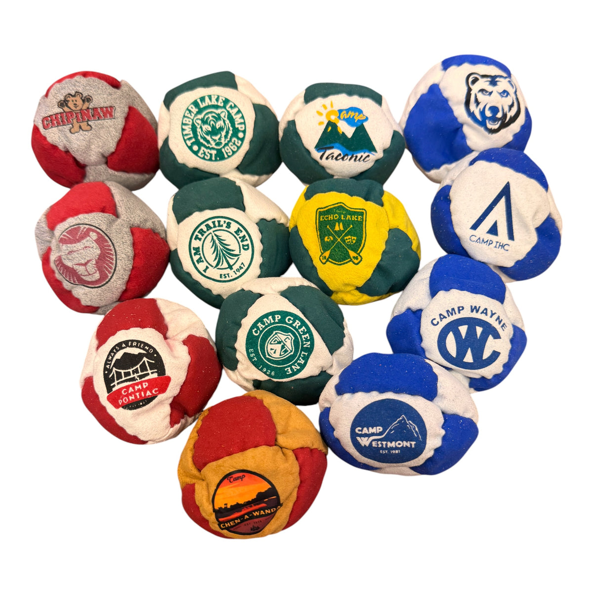 Collection of twelve colorful camp logo hacky sacks featuring different summer camps including Chippewa, Timber Lake Camp, Camp Taconic, Camp Wayne, Echo Lake, Camp Pontiac, Camp Green Lane, Camp Chen-A-Wanda, and Camp Westmont
