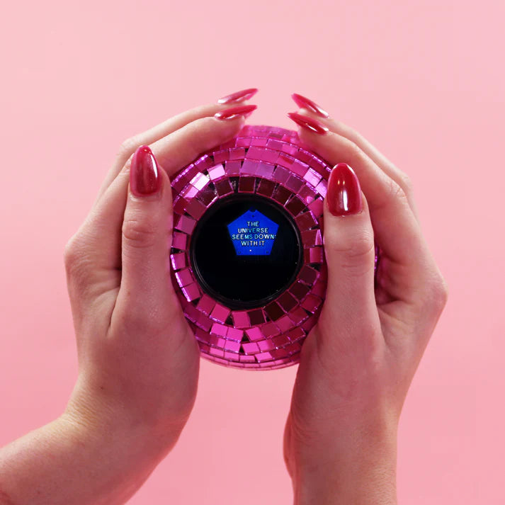 Hands holding a pink Disco Decision Ball whose screen reads The Universe Seems Down With It