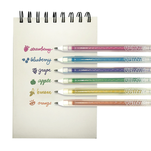 Six scented metallic gel pens displayed on notepad showing strawberry, blueberry, grape, apple, banana and orange flavors with corresponding colored barrels