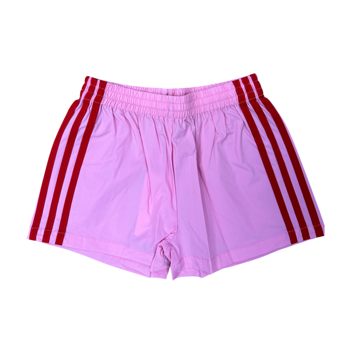 Pink 70s style athletic shorts with red and light pink vertical side stripes and elastic waistband, flat lay on white background