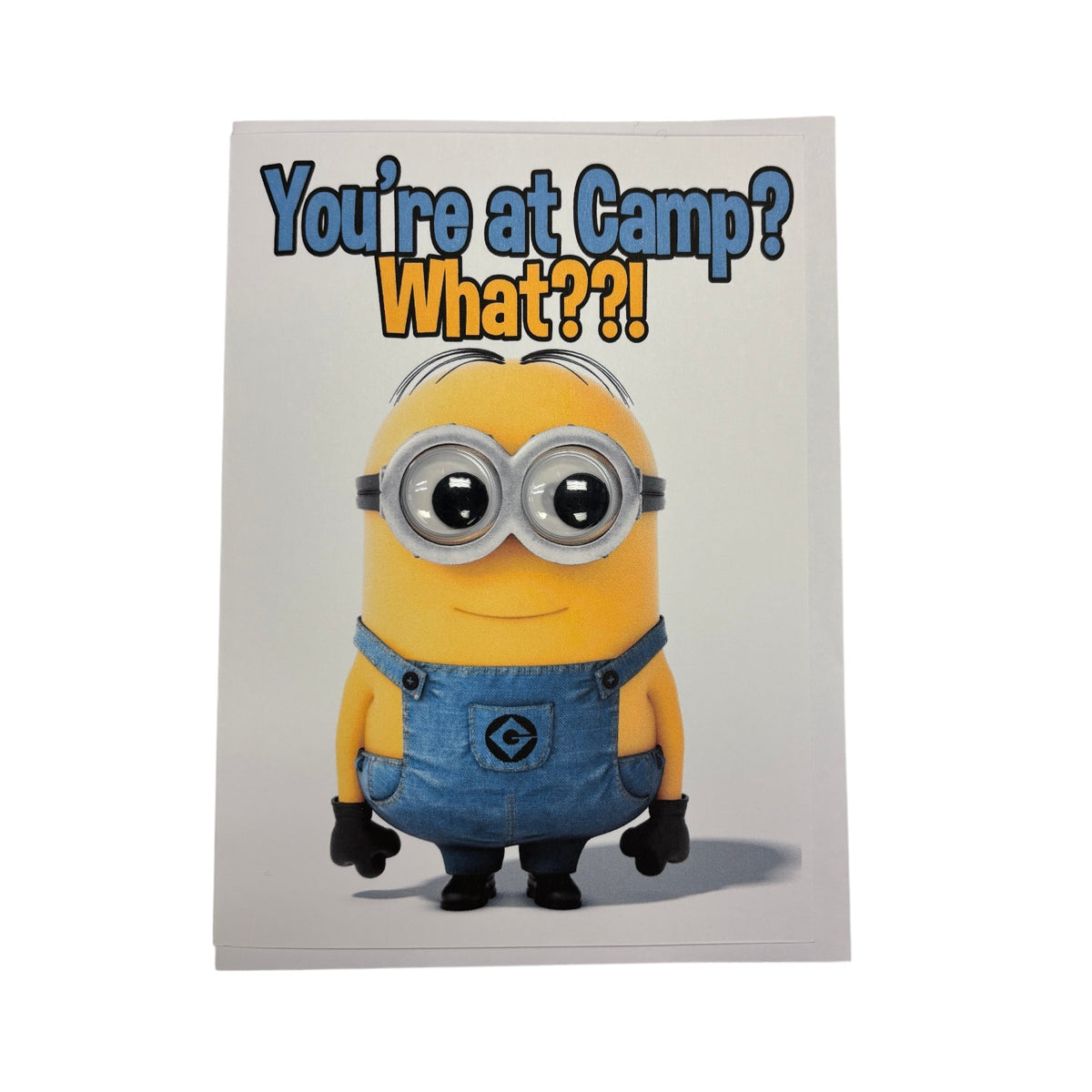 Minion wiggly eye greeting card with yellow Minion character in blue denim overalls with real googly eyes and text reading You're at Camp What??! on white background