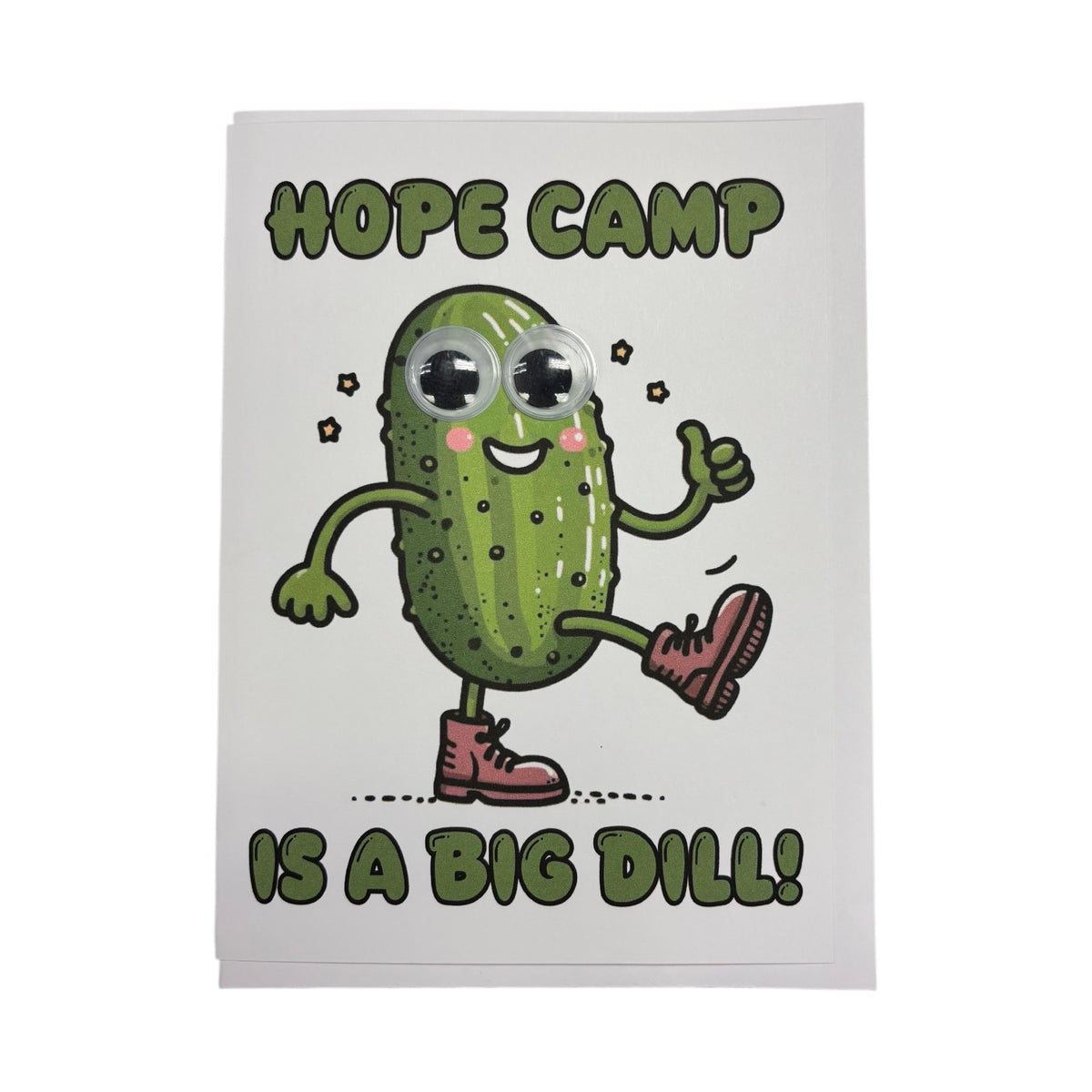 Hope Camp Is A Big Dill funny greeting card featuring cheerful green pickle character with googly wiggly eyes, rosy pink cheeks, red boots giving thumbs up with stars around it, blank inside for camp mail