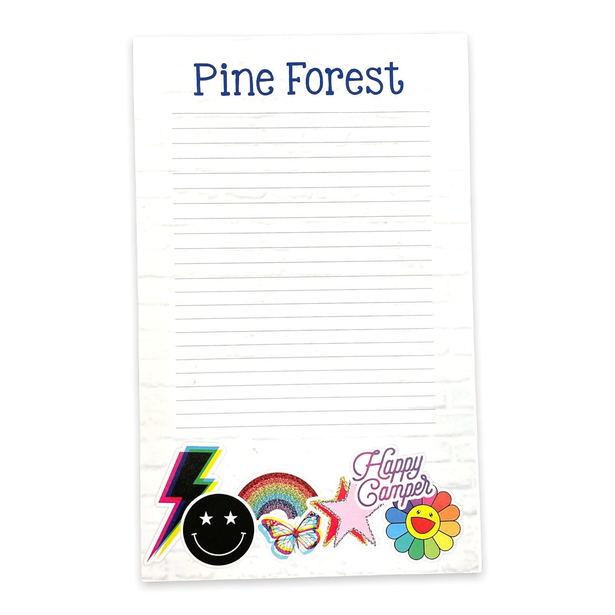 Close-up of Happy Camper Grunge notepad showing Pine Forest title, lined paper, and colorful grunge stickers including lightning bolt, smiley face, rainbow, butterfly and flower