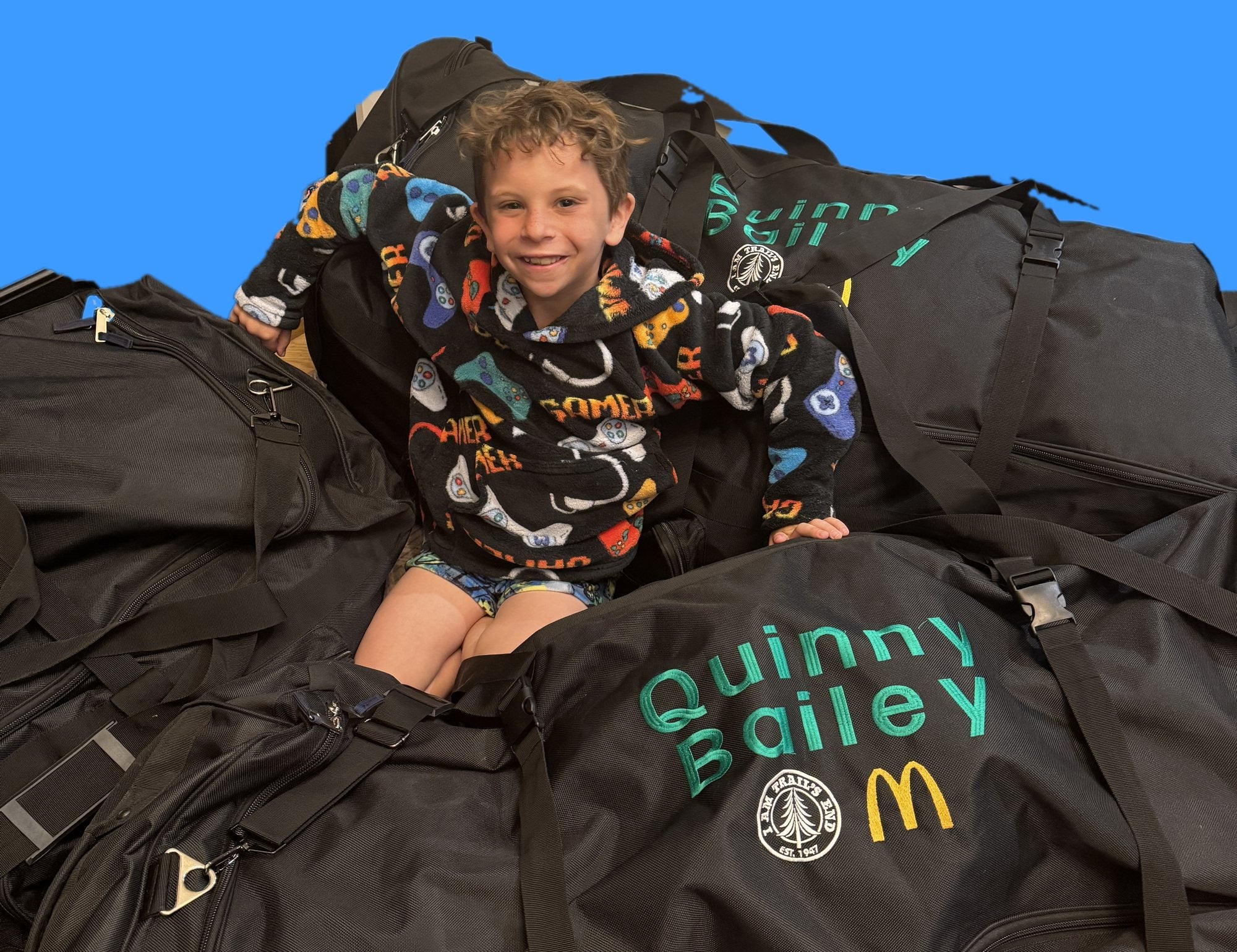 Boy sitting on his personalized camp duffels